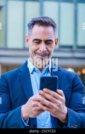 Confident businessman using smartphone outdoors.Vertical Stock Photo