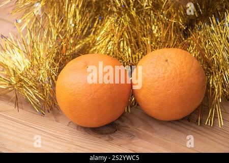 Two oranges on the table, tinsel around them, a New Year's atmosphere. Stock Photo