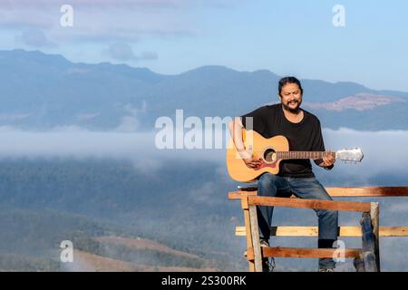 A man playing guitar while Travel relax camping on vacation holiday weekend. Stock Photo