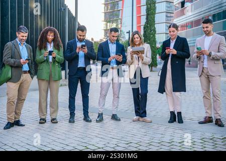Business people standing together using smartphones looking at camera outdoors Stock Photo