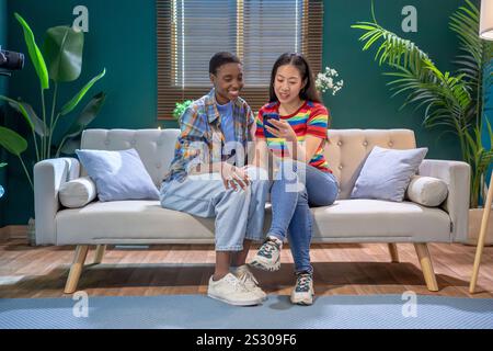Multiracial women with smartphone in the living room. Friends having fun. Stock Photo
