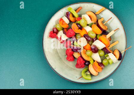 Appetizing fruit skewers made from fresh fruits on wooden skewers. Space for text. Stock Photo