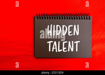 Hidden talent message written on black notebook page with red background. Conceptual hidden talent symbol. Copy space. Stock Photo