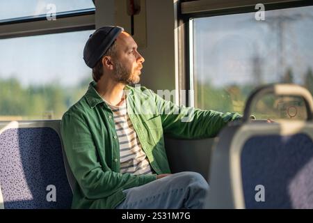 Tourist immersed in thoughts looking through window, traveling by train, observing passing scenery Stock Photo