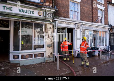 Emergency services attend the scene pumping water out of the basement of The Vaults pub and a neighbouring property as people in the Worcestershire town of Tenbury Wells clean up silt and mud following flooding during Storm Bert on 25th November 2024 in Tenbury Wells, United Kingdom. As heavy rainfall from Storm Bert impacted right across the UK, the town of Tenbury Wells flooded after river levels at Kyre Brook rose, causing a wall to collapse on Market Street allowing flood waters to fill the town, inundating properties. Further damage was caused by a tractor being driven through the flooded Stock Photo