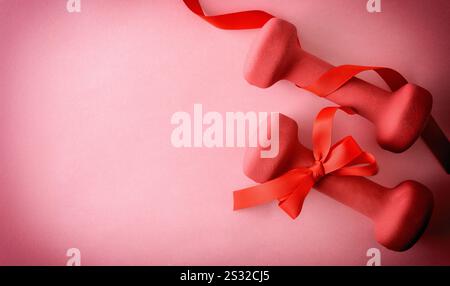 Workout session gift concept with pink dumbbells with bow isolated on pink background. Top view. Stock Photo