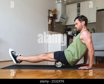 Caucasian man doing sports exercise at home using foam roller. Stock Photo