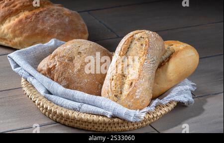 Loaves of bread in a basket on a kitchen table. Stock Photo