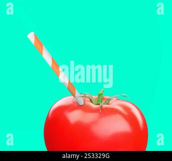 Drinking straw sticking out of fresh tomato on turquoise background. Freshly made juice or smoothie concept Stock Photo