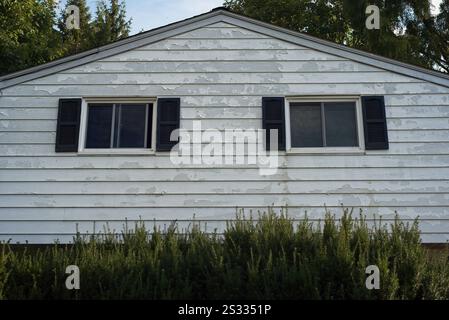 Detail of peeling paint on the aluminum siding on the upper level of a split-level house Stock Photo