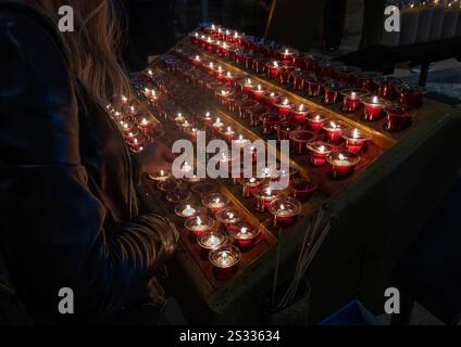 Woman lights votive candles in the Basilica of Sacre Coeur, Montmartre, Paris, France Stock Photo
