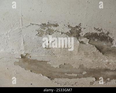 chalky shabby surface with cracks and fallen off parts of whitewash, concrete wall or ceiling with a fragment of fallen off old plaster Stock Photo