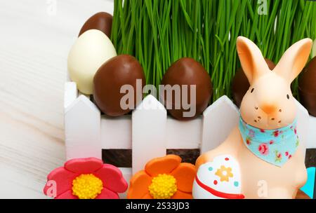 Sugar bunny and Easter chocolate eggs on green grass background. Easter composition. Stock Photo
