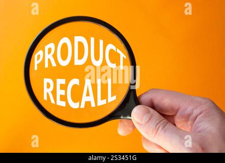 Product recall symbol. Concept words Product recall on magnifying glass. Beautiful orange background. Businessman hand. Business and Product recall co Stock Photo