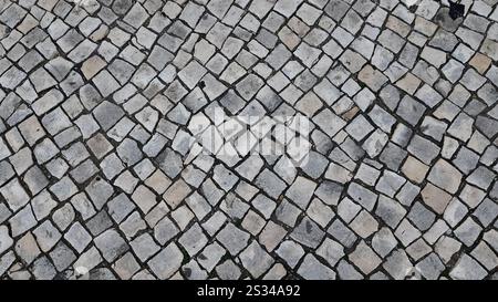 Close-up view of a cobbled stone street in Portugal, showcasing intricate patterns of calçada portuguesa. (Portuguese: "Calçada portuguesa") Stock Photo