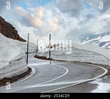 Spring cloudy overcast mountain landscape with serpentine road on Furka Pass, Switzerland. Stock Photo