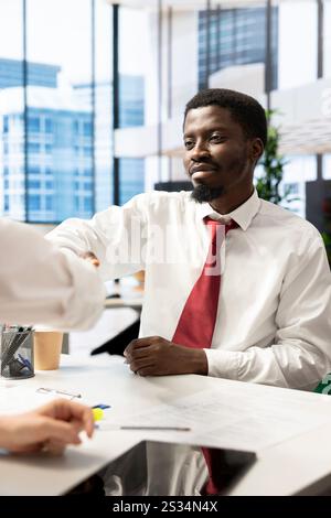HR worker reviewing happy candidate, doing handshake after asking questions about qualifications. Cheerful applicant at interview closing deal after proving skills and enthusiasm for job opportunity Stock Photo
