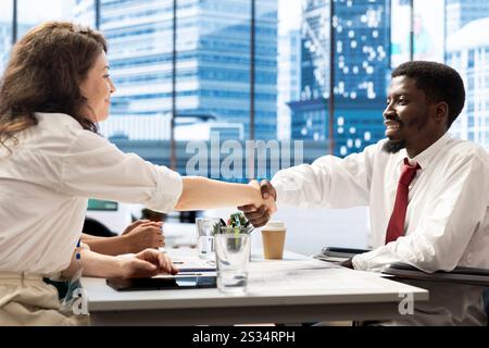 HR expert doing handshake with person with disability, vetting applicants to ensure skills match role needs. Headhunter talking with man in wheelchair, shaking hands after assessing work experience Stock Photo