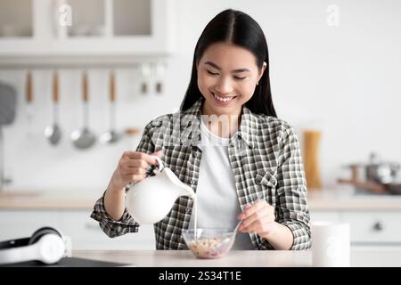 Happy young asian woman eating healthy oatmeal Stock Photo