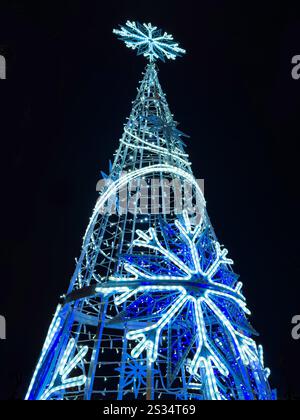 Illuminated Christmas tree at night with blue LED lights and large snowflake decorations, creating a festive holiday atmosphere Hanley stoke on Trent Stock Photo