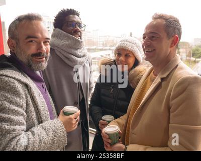 Four office workers on a coffee break in a business district. One looks at the camera with a confident expression, as if knowing something the others Stock Photo
