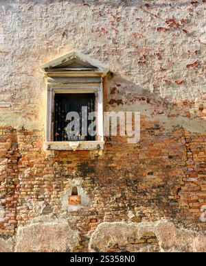 White window on old house wall Cracks in concrete visible red bricks in Venice, Italy. Stock Photo