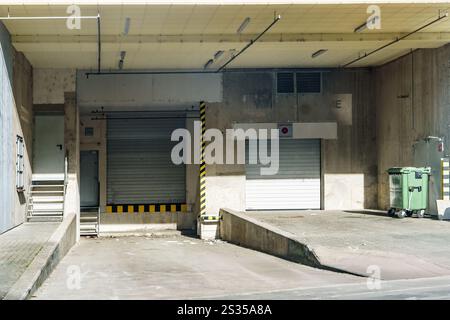 Empty loading docks with closed shutter doors are waiting for trucks and delivery at a warehouse Stock Photo