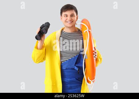 Male sailor with rescue ring and binoculars on light background Stock Photo