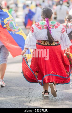 Woman wearing traditional andean dress with ecuadorian flag walking in a parade celebrating hispanic culture Stock Photo