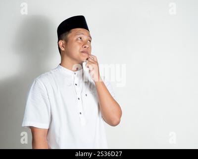 Moslem Asian man thinking and concentrating. Man holding his chin while looking for ideas over white background Stock Photo
