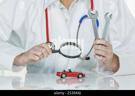 A model of a car is examined by a doctor. Symbol photo for workshop, service and car purchase Stock Photo