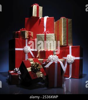 Huge pile of Christmas gift boxes illuminated in darkness isolated on blue black background Stock Photo