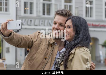 A young couple take a self-portrait with a mobile phone. Selfies are in. Austria Stock Photo