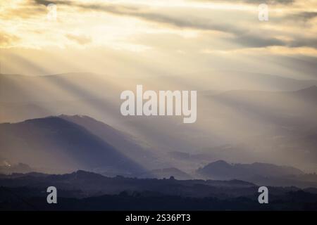 Sunbeams break through the clouds over a mountain landscape Stock Photo
