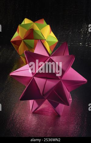 Stock photo of a Light-painted colorful Origami abstract figures polyhedras made from folded paper on dark silvery shining background Stock Photo