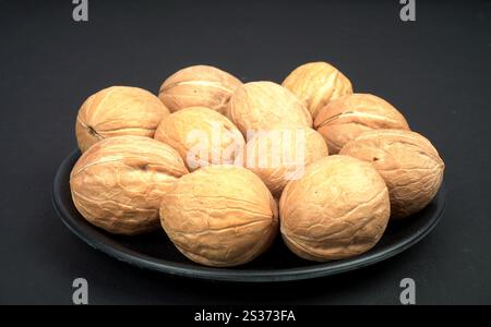 One full plate of dry walnut in black background Stock Photo
