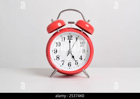 Red alarm clock set at five o'clock on table isolated on white background close-up with clipping path Stock Photo