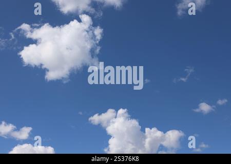 white puffy clouds floating against deep blue skies Stock Photo