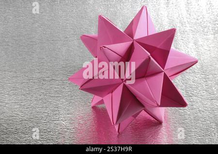 Abstract purple Origami polyhedron figure on silvery background Stock Photo