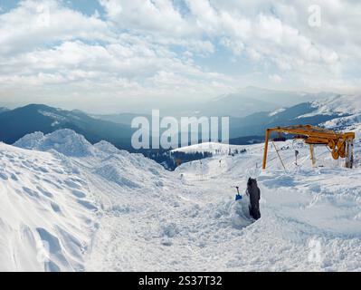 Snow-covered ski hoist ropeway (upper  terminal) and mountain landscape behind (Ukraine, Carpathian Mt's, Drahobrat ski resort). Stock Photo