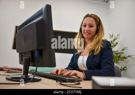 Businesswoman wearing headset working with desktop computer in modern office Stock Photo