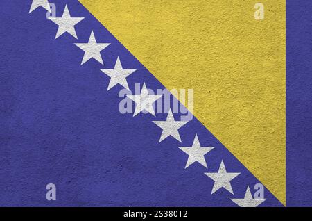 Bosnia and Herzegovina flag depicted in bright paint colors on old relief plastering wall close up. Textured banner on rough background. Bosnia and Stock Photo