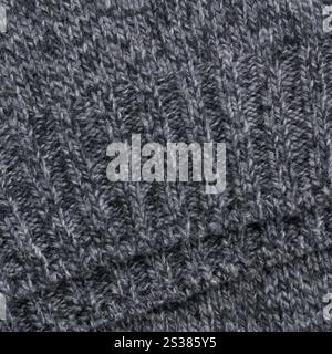 A macro shot of the hem of a grey melange wool sweater, showcasing the ribbed knit detail. The image highlights the soft texture of the knit fabric an Stock Photo