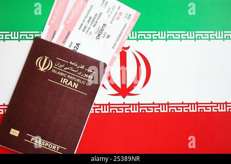 Red Islamic Republic of Iran passport with airline tickets on Iranian flag background close up. Tourism and travel concept Stock Photo