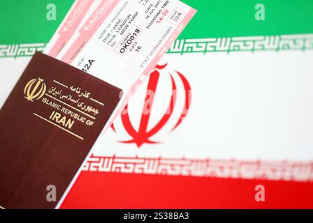 Red Islamic Republic of Iran passport with airline tickets on Iranian flag background close up. Tourism and travel concept Stock Photo