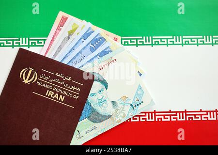 Red Islamic Republic of Iran passport and iranian reals money bills background close up. Tourism and travel concept Stock Photo