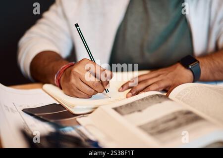 Hands, writing and man in university studying for civil engineering exam, test or assignment. Textbooks, research and male student with notes for Stock Photo