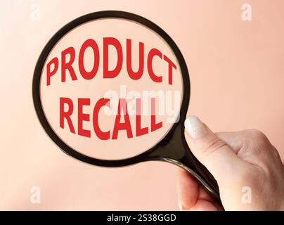 Product recall symbol. Concept words Product recall on magnifying glass. Beautiful pink background. Businessman hand. Business and Product recall conc Stock Photo