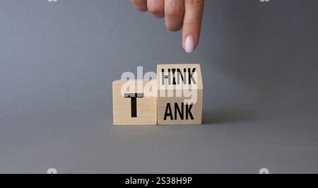 Think Tank symbol. Businessman hand points at turned wooden cubes with words Think Tank. Beautiful grey background. Business and Think Tank concept. C Stock Photo