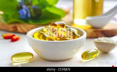 A bowl filled with fish oil sits on a table next to a spoon. The clear liquid glistens under the light, ready for consumption or use. Stock Photo